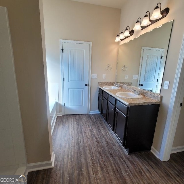 full bathroom with a sink, baseboards, and wood finished floors