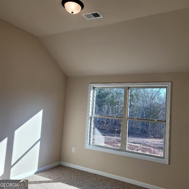 carpeted empty room with lofted ceiling, plenty of natural light, visible vents, and baseboards