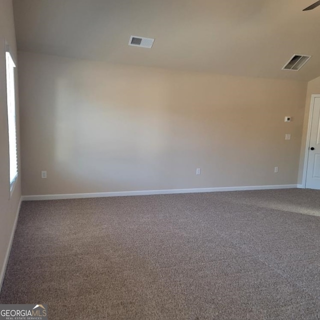 spare room featuring baseboards, visible vents, and carpet flooring