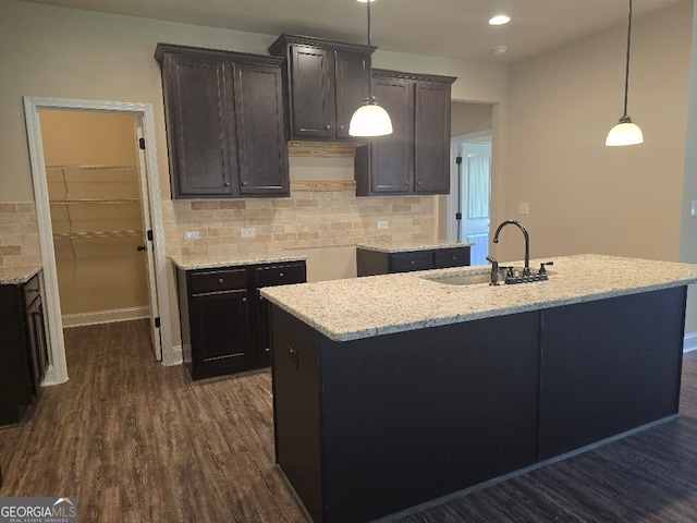 kitchen featuring decorative light fixtures, dark wood-type flooring, backsplash, and sink