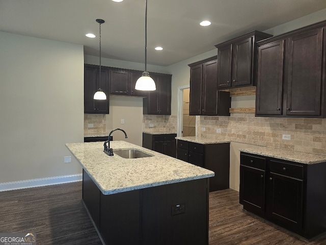 kitchen featuring an island with sink, dark wood-type flooring, sink, and tasteful backsplash