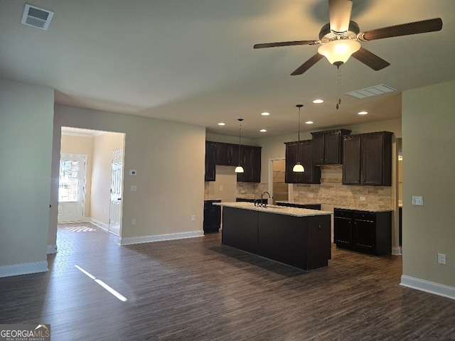 kitchen featuring decorative backsplash, dark hardwood / wood-style floors, a kitchen island with sink, and sink