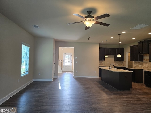 kitchen featuring sink, dark wood-type flooring, an island with sink, and plenty of natural light