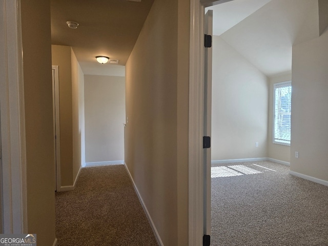 hallway with carpet flooring and lofted ceiling