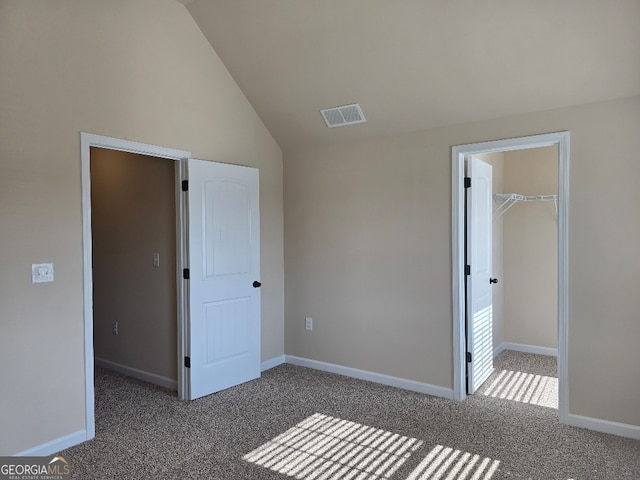 unfurnished bedroom with lofted ceiling, a spacious closet, dark colored carpet, and a closet