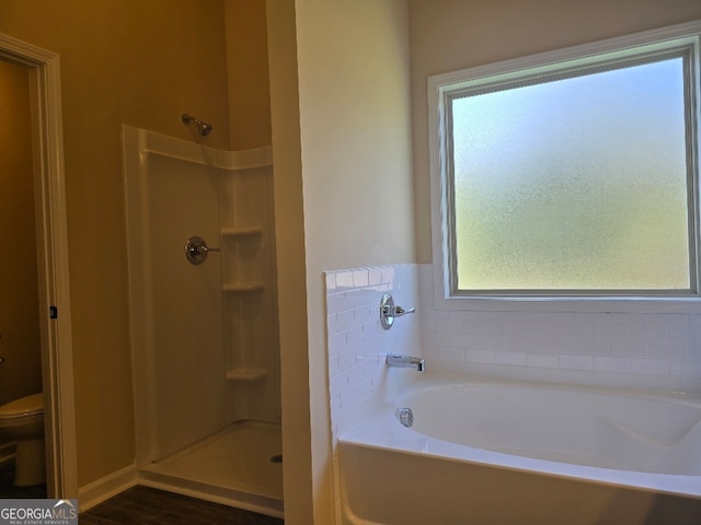 bathroom with hardwood / wood-style floors, toilet, and plus walk in shower