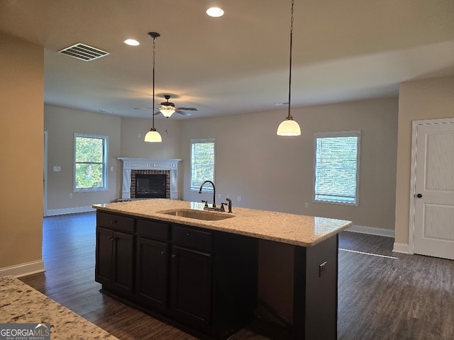 kitchen with pendant lighting, light stone countertops, sink, and dark hardwood / wood-style flooring