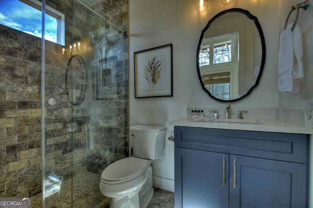 bathroom with a shower with door, vanity, and toilet