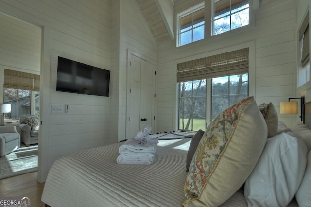 bedroom featuring multiple windows and wood walls