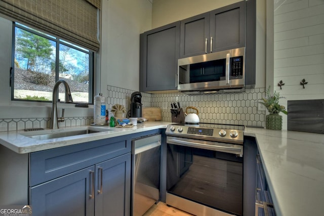 kitchen featuring decorative backsplash, light stone counters, sink, and stainless steel appliances