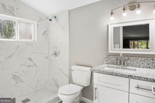 bathroom featuring vanity, a healthy amount of sunlight, toilet, and a tile shower