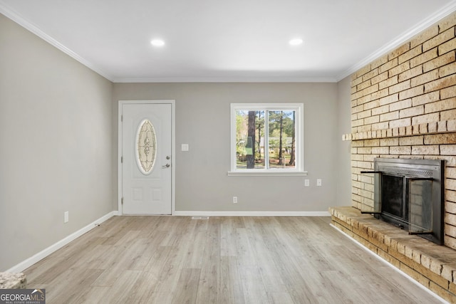 foyer entrance featuring a fireplace, light wood-type flooring, and crown molding