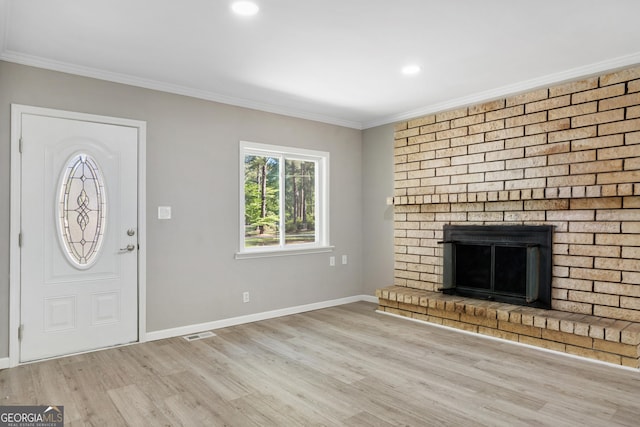 unfurnished living room with light hardwood / wood-style floors, ornamental molding, and a brick fireplace