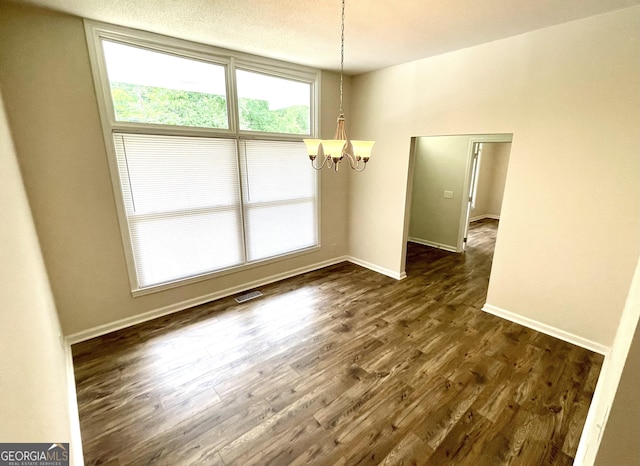 unfurnished dining area featuring dark hardwood / wood-style flooring and a notable chandelier