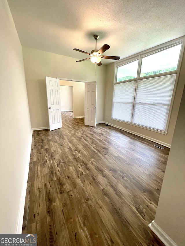 unfurnished bedroom featuring a textured ceiling, ceiling fan, and dark hardwood / wood-style floors