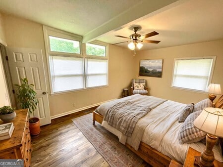 bedroom with beamed ceiling, ceiling fan, and dark wood-type flooring