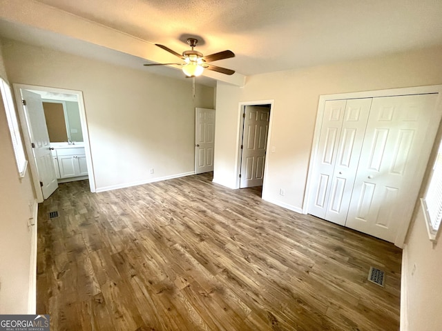 unfurnished bedroom with hardwood / wood-style flooring, ensuite bathroom, and ceiling fan