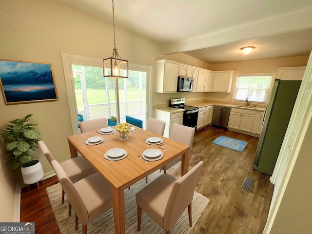 dining room with beamed ceiling, a healthy amount of sunlight, sink, and dark wood-type flooring