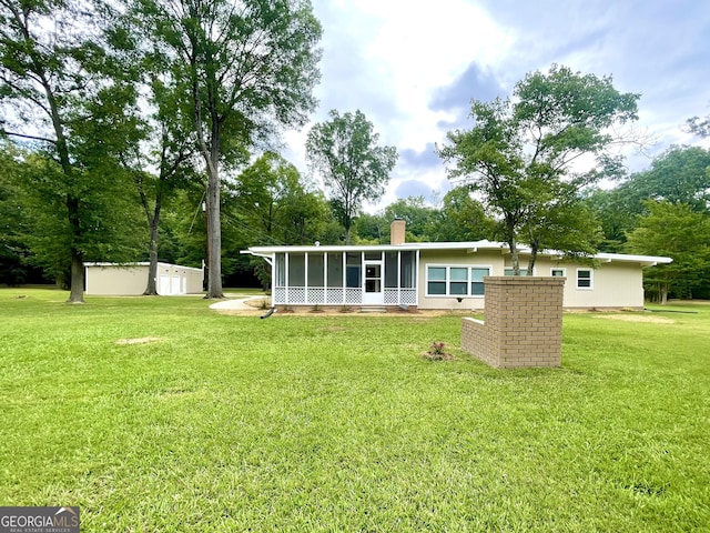 rear view of property featuring a lawn and a sunroom