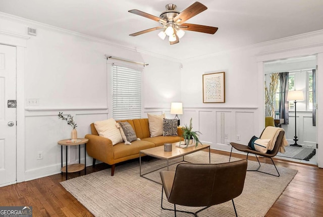 living room with dark wood-type flooring, ornamental molding, and ceiling fan