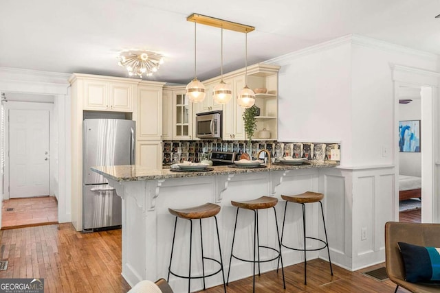 kitchen with appliances with stainless steel finishes, pendant lighting, light stone countertops, and backsplash