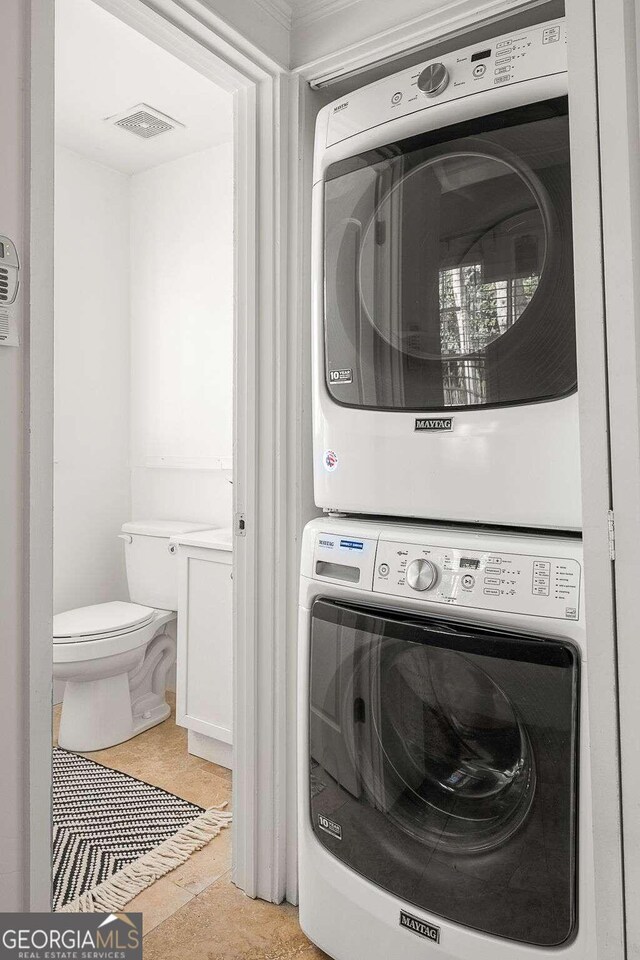 washroom featuring stacked washer and clothes dryer and light tile patterned floors