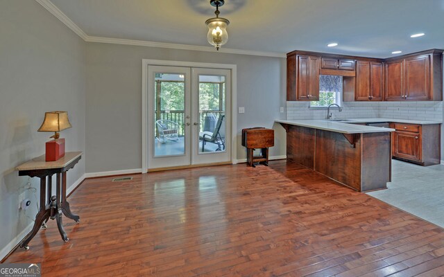 kitchen with dark hardwood / wood-style floors, kitchen peninsula, backsplash, a kitchen breakfast bar, and french doors