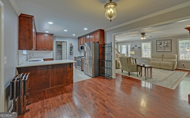 kitchen featuring appliances with stainless steel finishes, sink, backsplash, and light hardwood / wood-style flooring