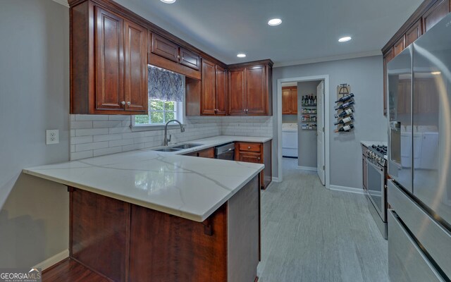 kitchen with kitchen peninsula, stainless steel fridge, light stone counters, backsplash, and sink