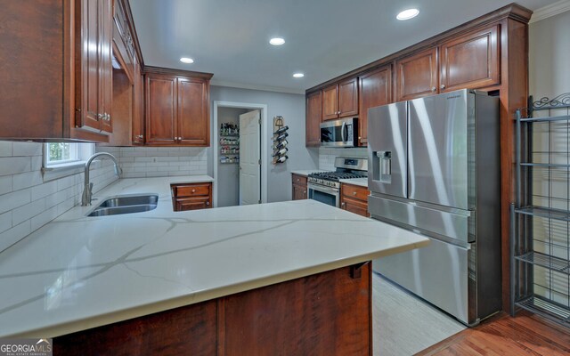 kitchen featuring kitchen peninsula, backsplash, light wood-type flooring, and stainless steel appliances