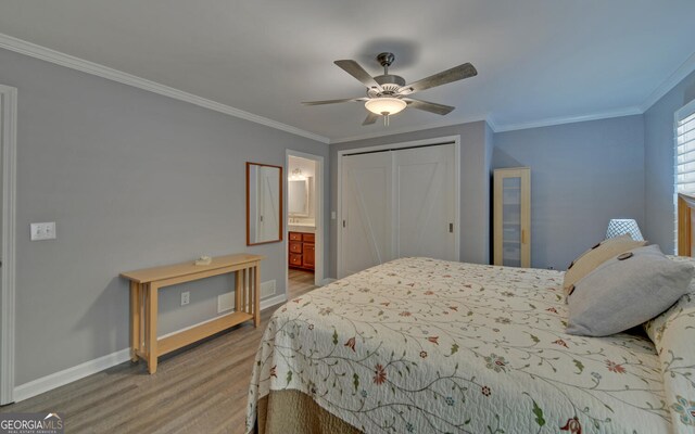 bedroom featuring ornamental molding, ensuite bath, hardwood / wood-style floors, a closet, and ceiling fan