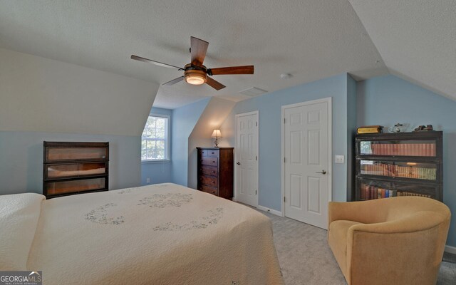 bedroom featuring carpet, ceiling fan, vaulted ceiling, and a textured ceiling