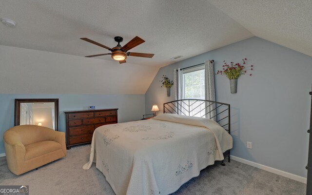 carpeted bedroom with a textured ceiling, ceiling fan, and vaulted ceiling