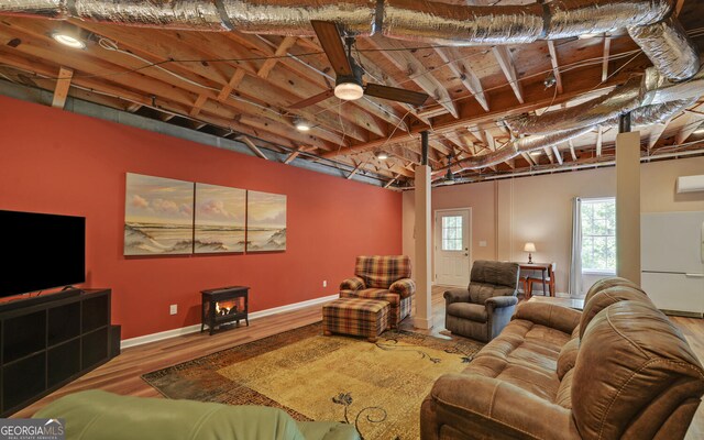 living room with ceiling fan, hardwood / wood-style flooring, and a wood stove