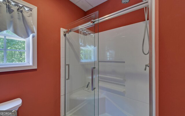 bathroom featuring a shower with door and toilet