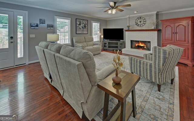 living room featuring crown molding, brick wall, a brick fireplace, hardwood / wood-style floors, and ceiling fan