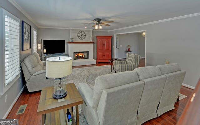 living room with dark hardwood / wood-style flooring, ceiling fan, a fireplace, and crown molding