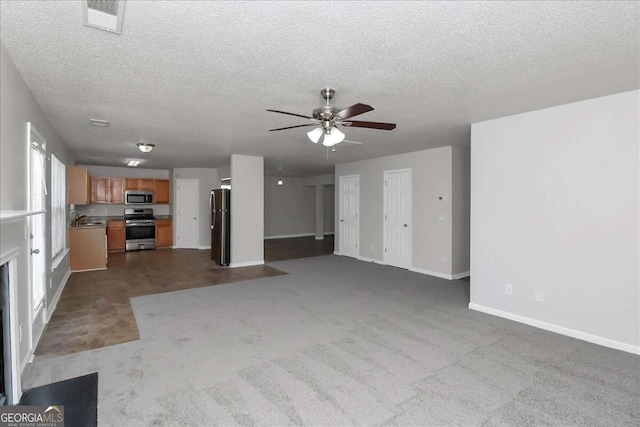 unfurnished living room with ceiling fan, sink, light colored carpet, and a textured ceiling