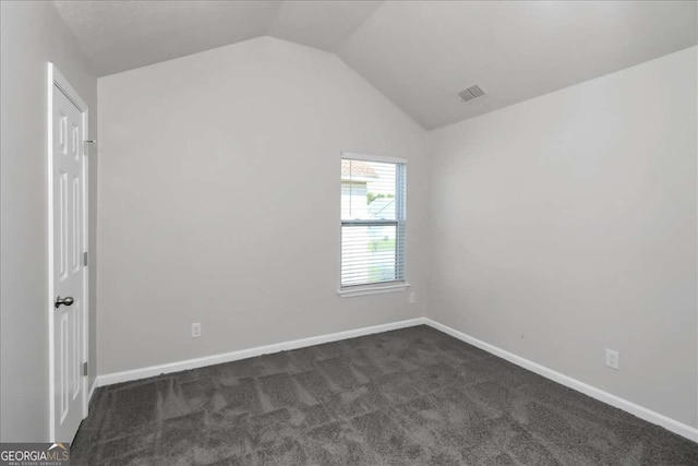 unfurnished room with dark colored carpet and vaulted ceiling