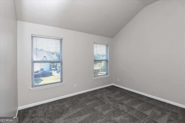 empty room with dark carpet and lofted ceiling