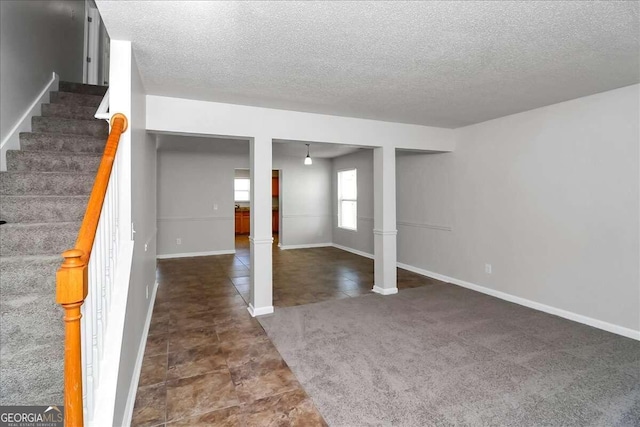 basement with a textured ceiling and dark colored carpet