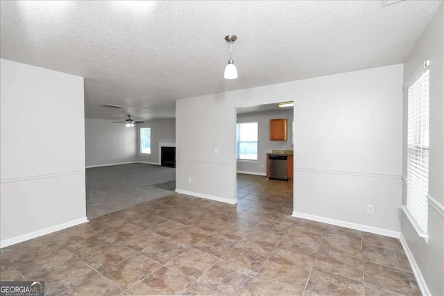 empty room with ceiling fan, a fireplace, and a textured ceiling