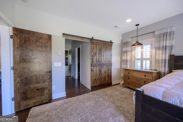 bedroom featuring a barn door and dark hardwood / wood-style flooring