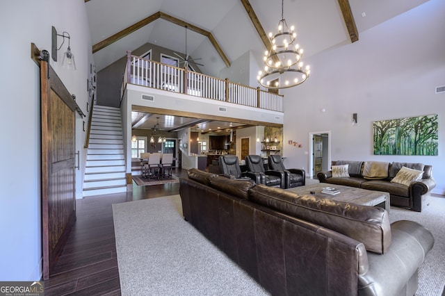 living room with ceiling fan with notable chandelier, dark hardwood / wood-style floors, high vaulted ceiling, and a barn door