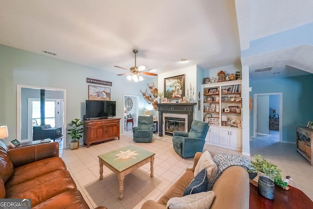 living room featuring ceiling fan, light tile patterned flooring, and a textured ceiling