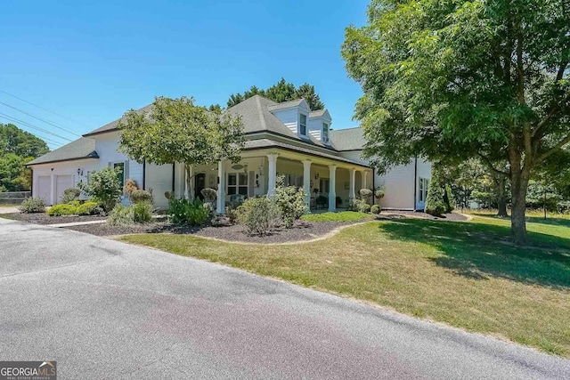 view of front of home with covered porch, a front yard, and a garage