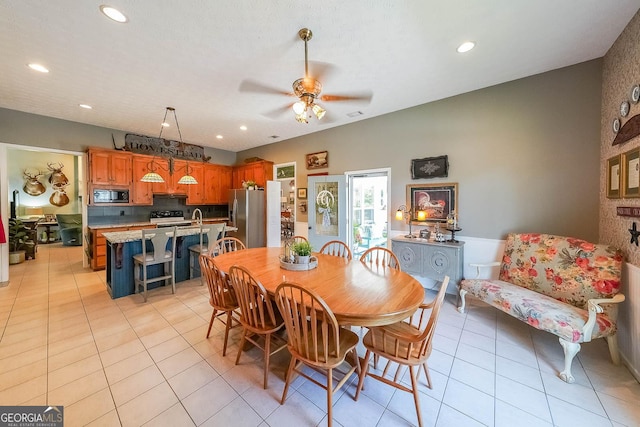 dining room featuring ceiling fan, light tile patterned floors, and sink