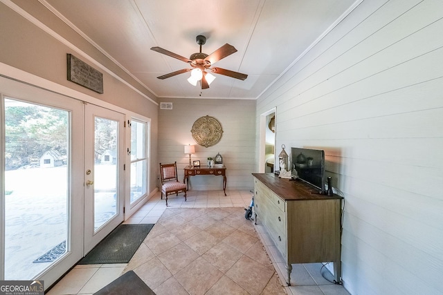 doorway to outside with light tile patterned flooring, french doors, ornamental molding, ceiling fan, and wood walls