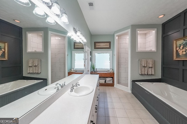 bathroom with plus walk in shower, a textured ceiling, vanity, and tile patterned floors