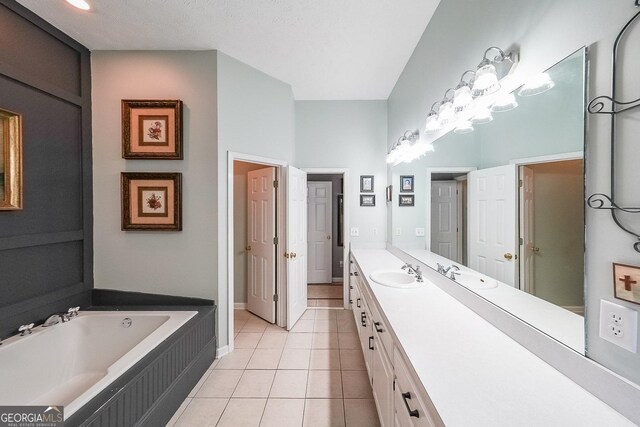 bathroom with tile patterned floors, a tub, vanity, and a textured ceiling